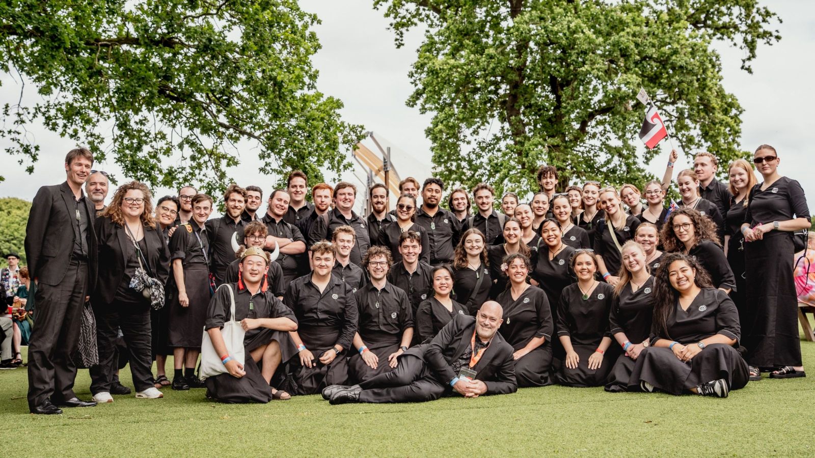 large group of young people standing on green lawn, smiling