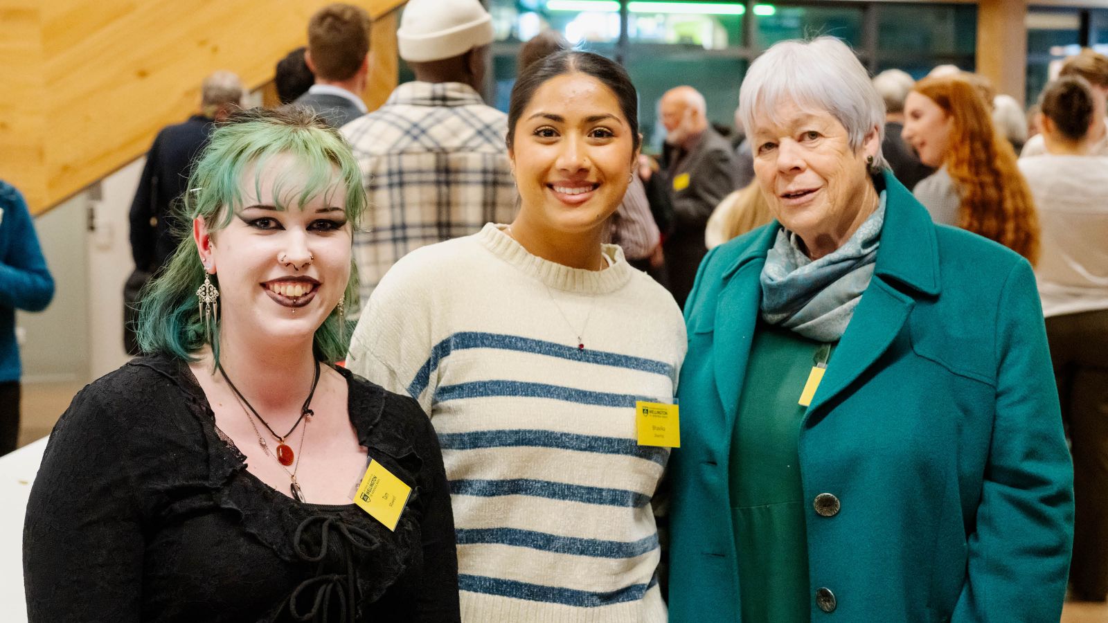 Three people stand smiling at the camera in Ngā Mokopuna
