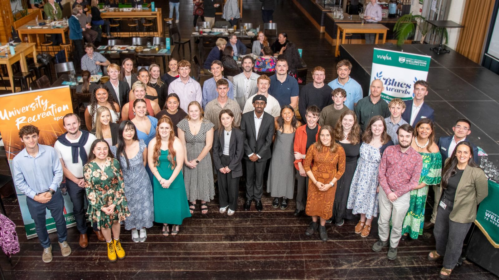 Blues award winners and university staff stand in a large semicircle and look up at the camera