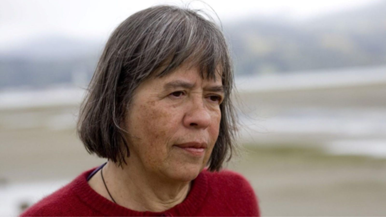Woman with short bob with seaside and hills in background