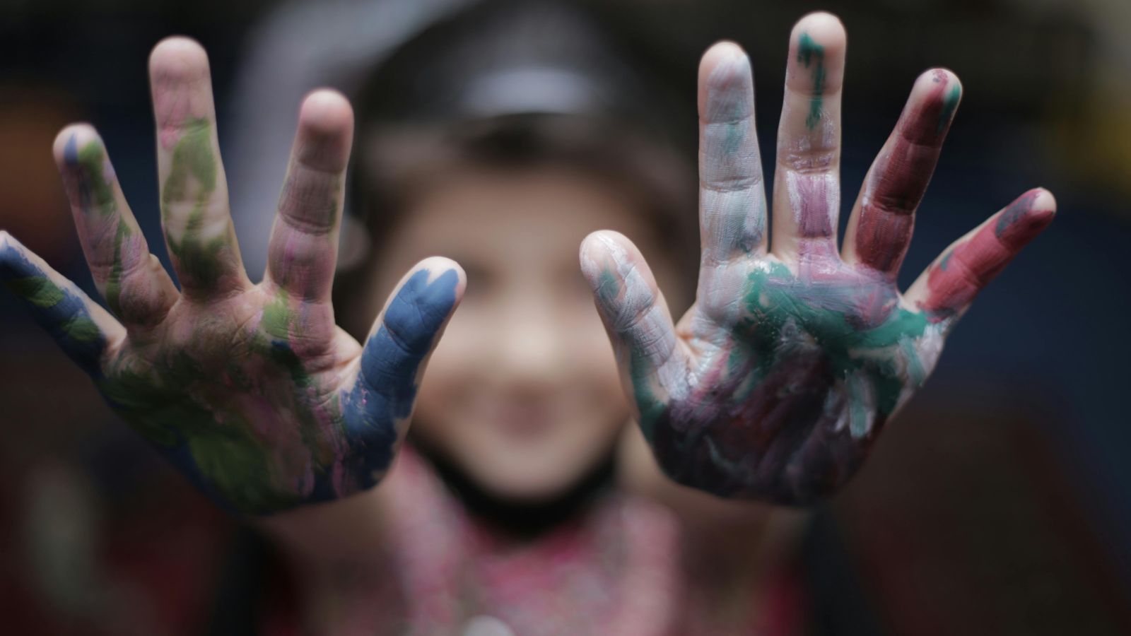 A child holding up their painted hands 