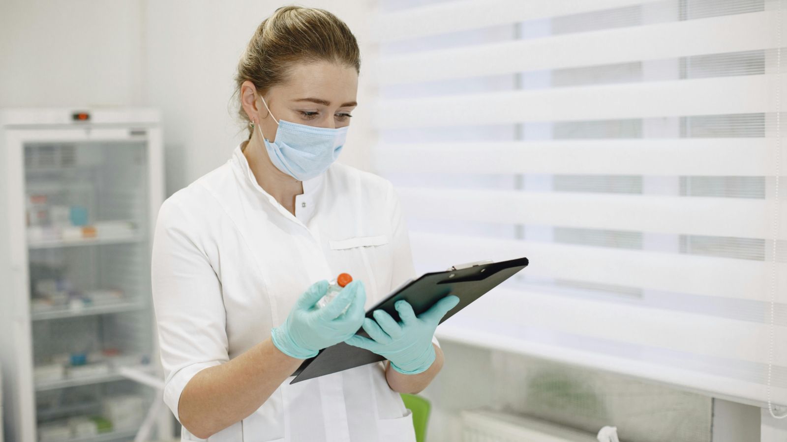 Health worker wearing face mask and gloves and holding a clipboard
