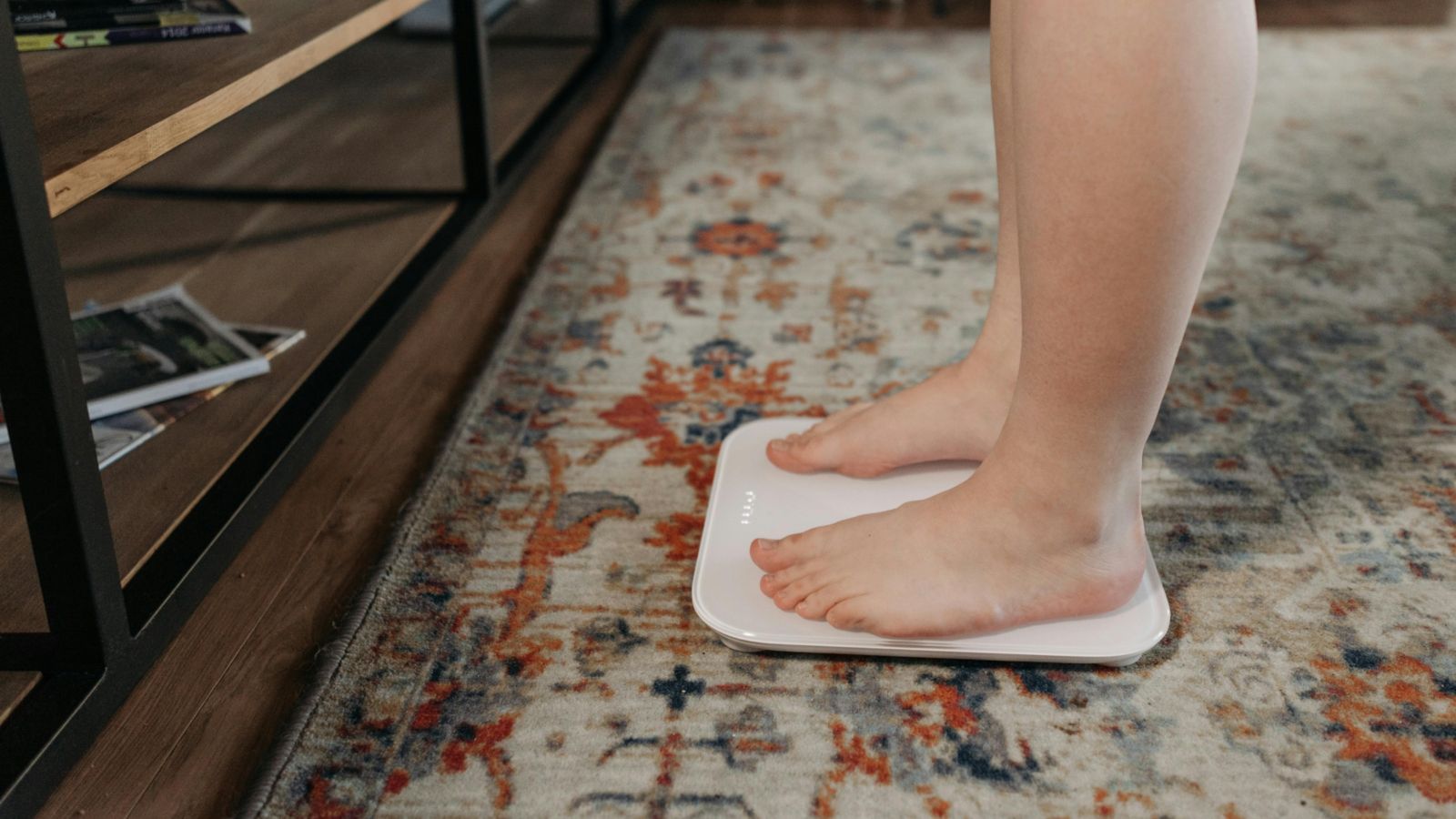 Person standing on scales placed on a patterned carpet 