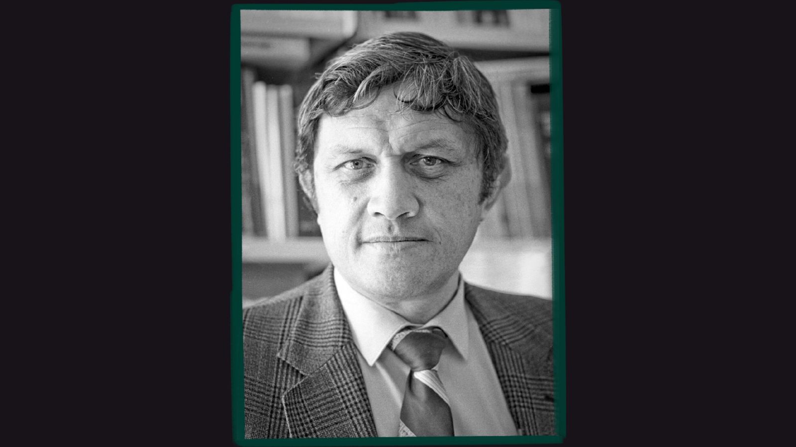 Young man with tie and plaid jacket looking sternly at camera