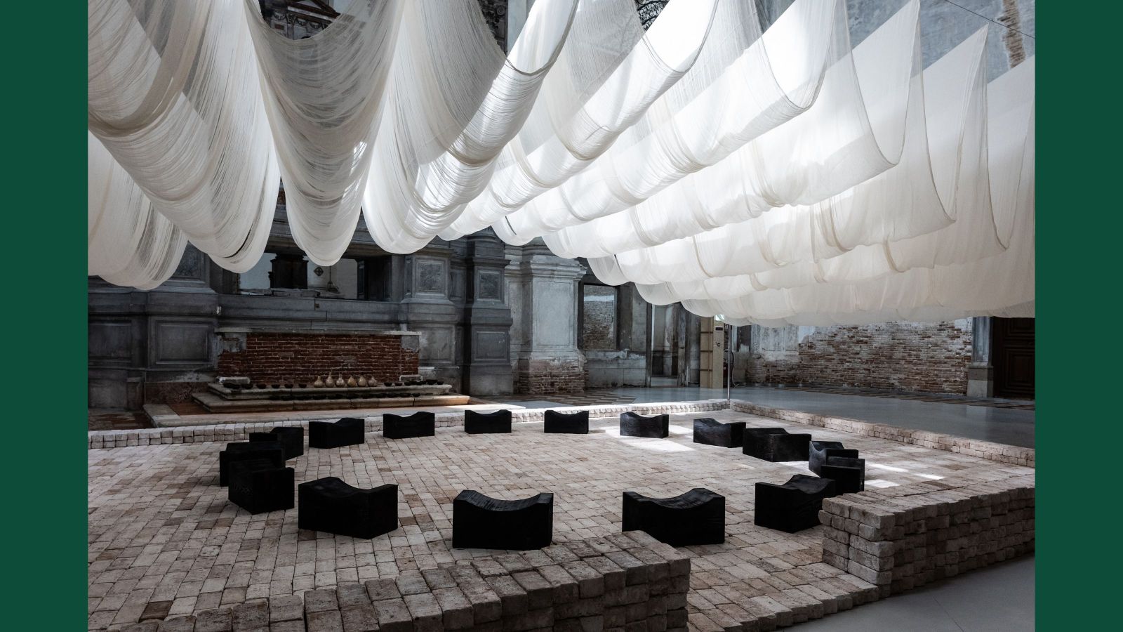 an artwork made up of brick, stone, and draped sails, representing a talking space at the front of a marae