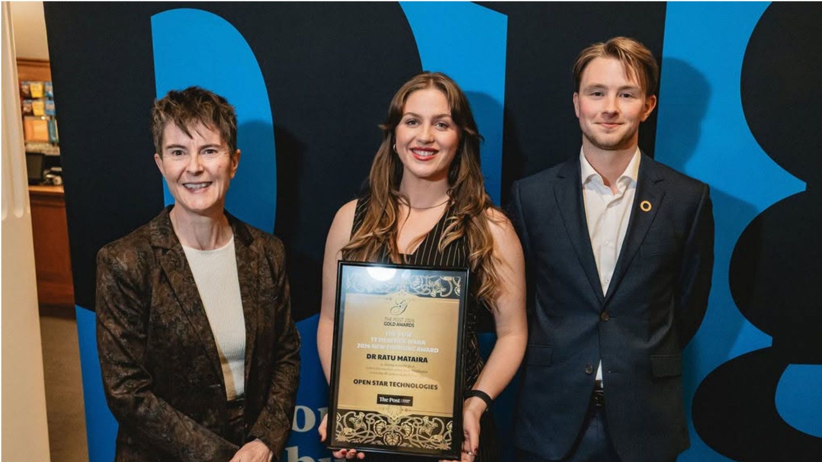 Three people standing holding an award, two women and one man
