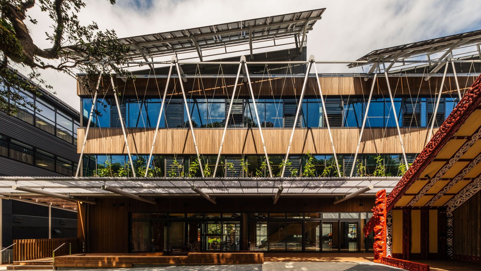 Wooden building with trees out the front and a wharenui marae at the side