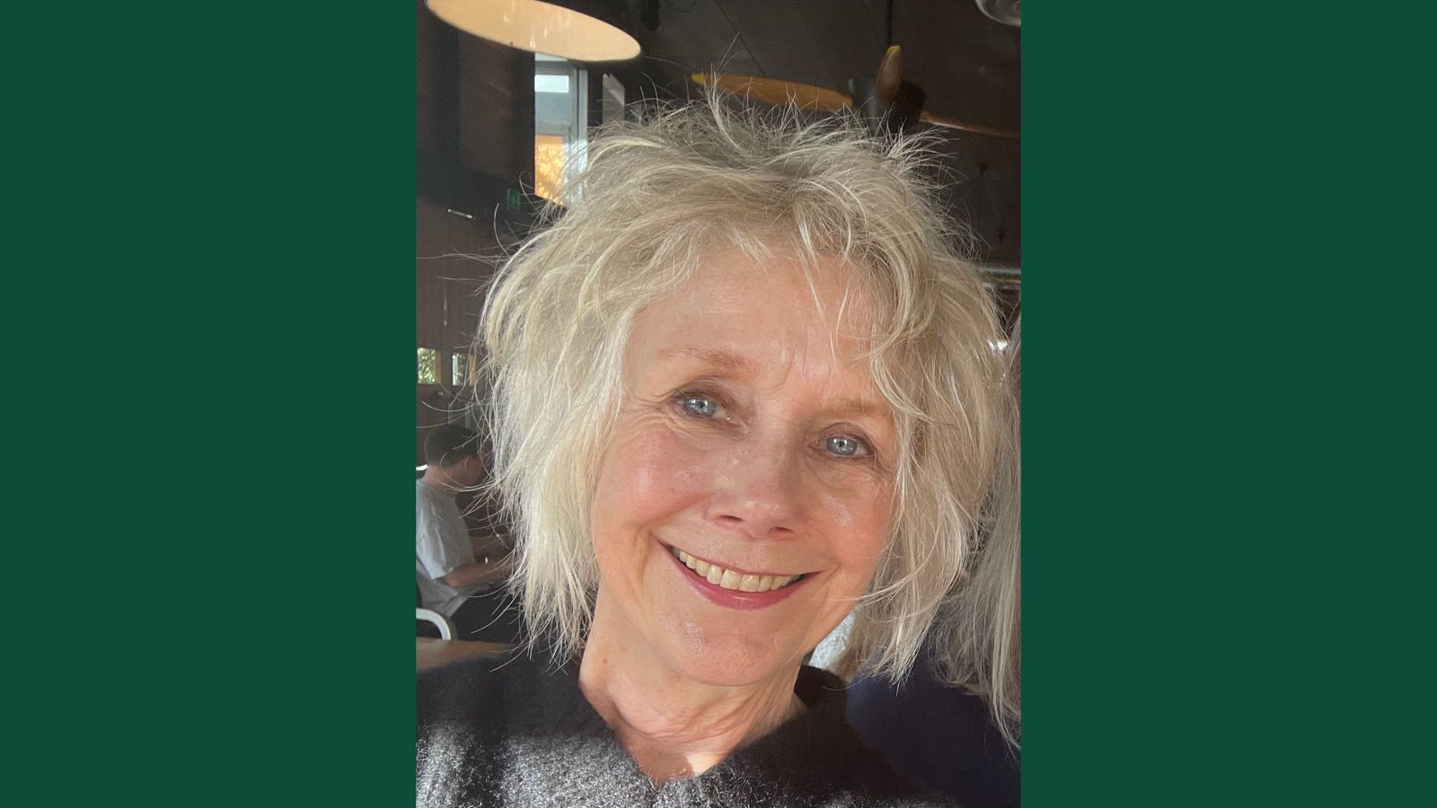Woman with wild blonde hair in a bob smiling widely