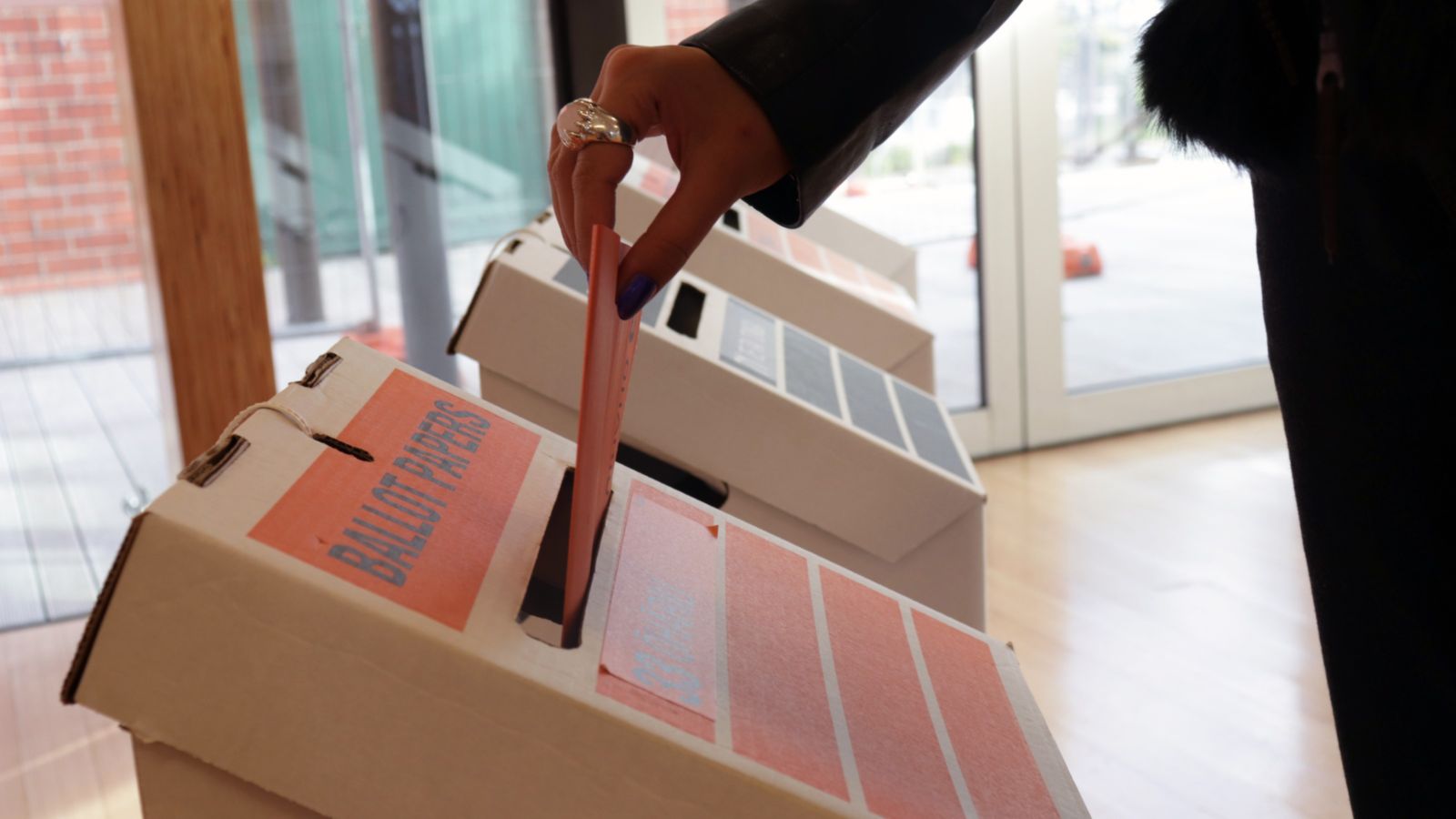 Person putting voting paper into ballot box