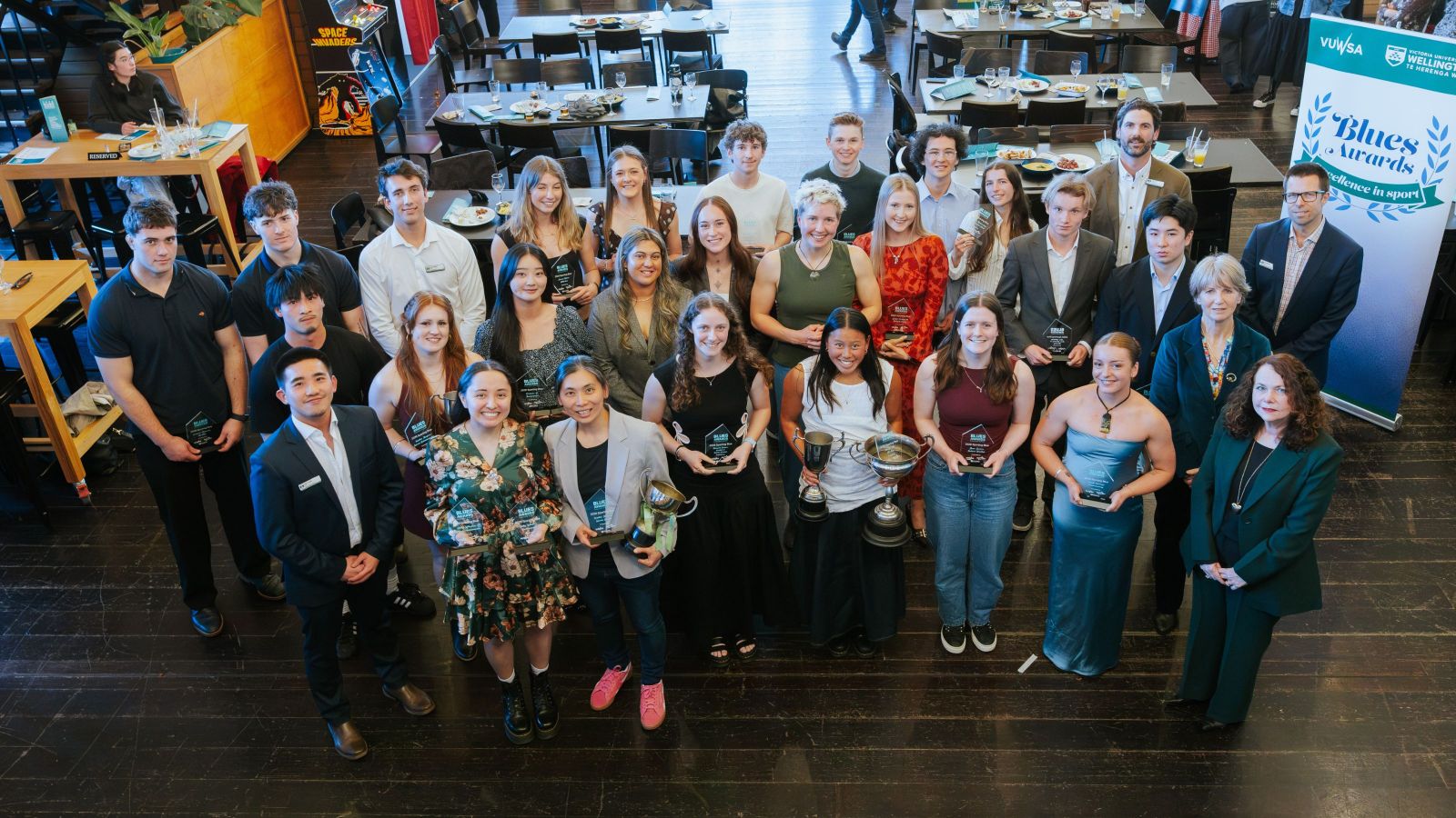 Blues award winners and university staff stand in a large semicircle and look up at the camera