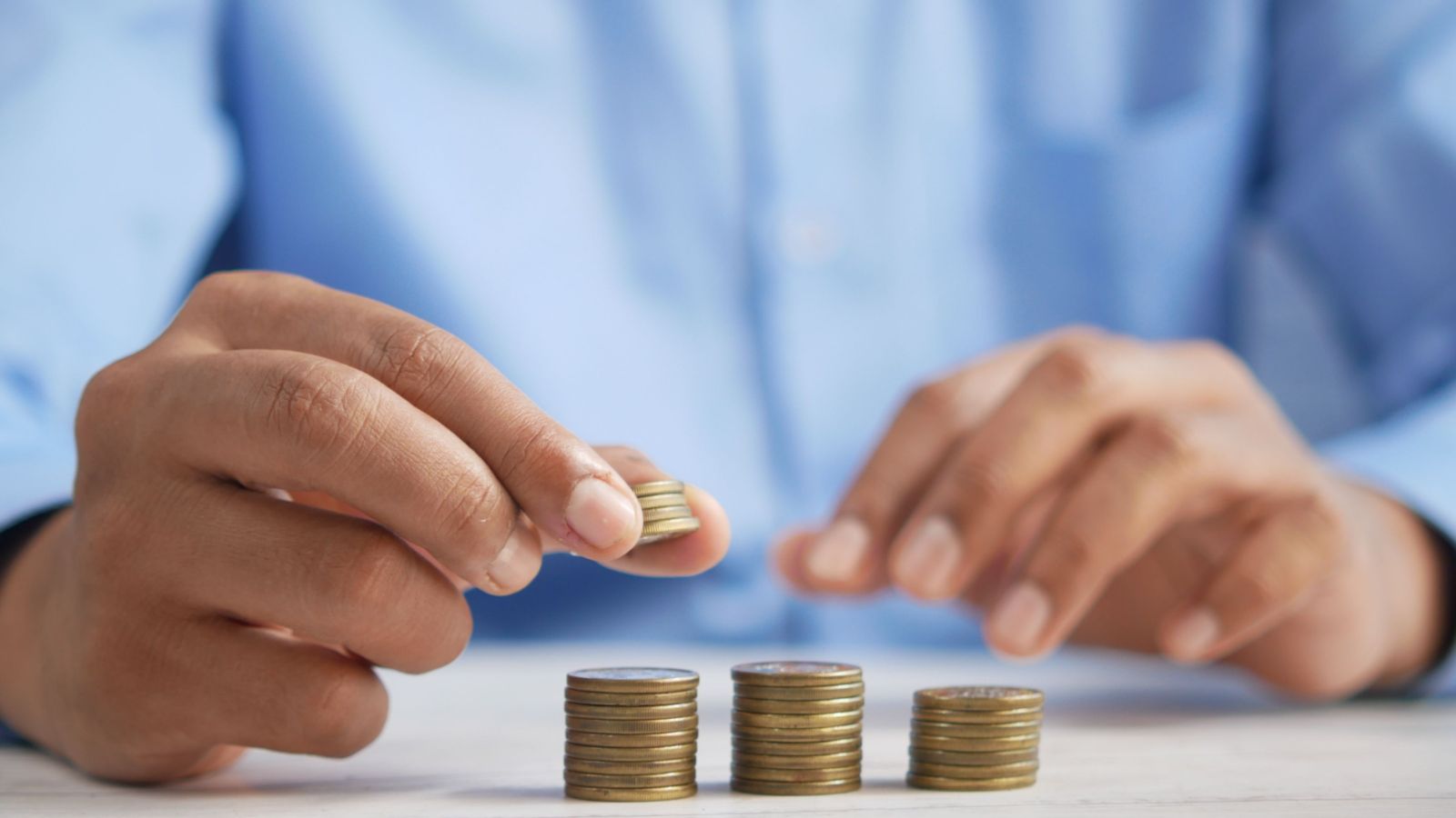 Close-up of person's hands stacking gold coins
