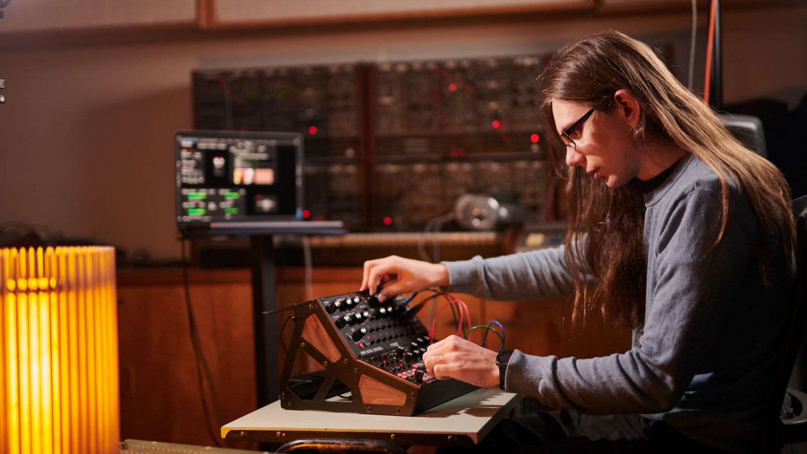 A student in a studio working at a soundboard.