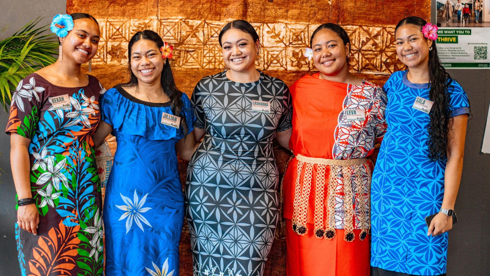 Group of five people in traditional attire smiling at the camera.