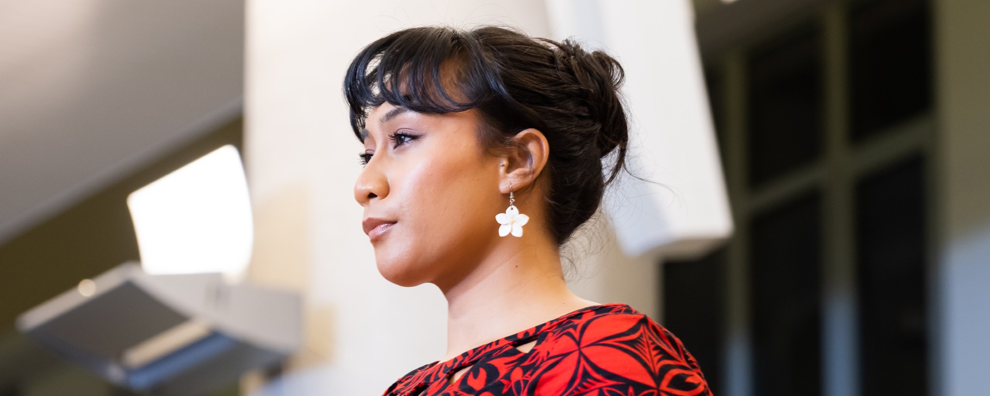 A profile photo of a student dressed in red, with a shiny silver flower earring.