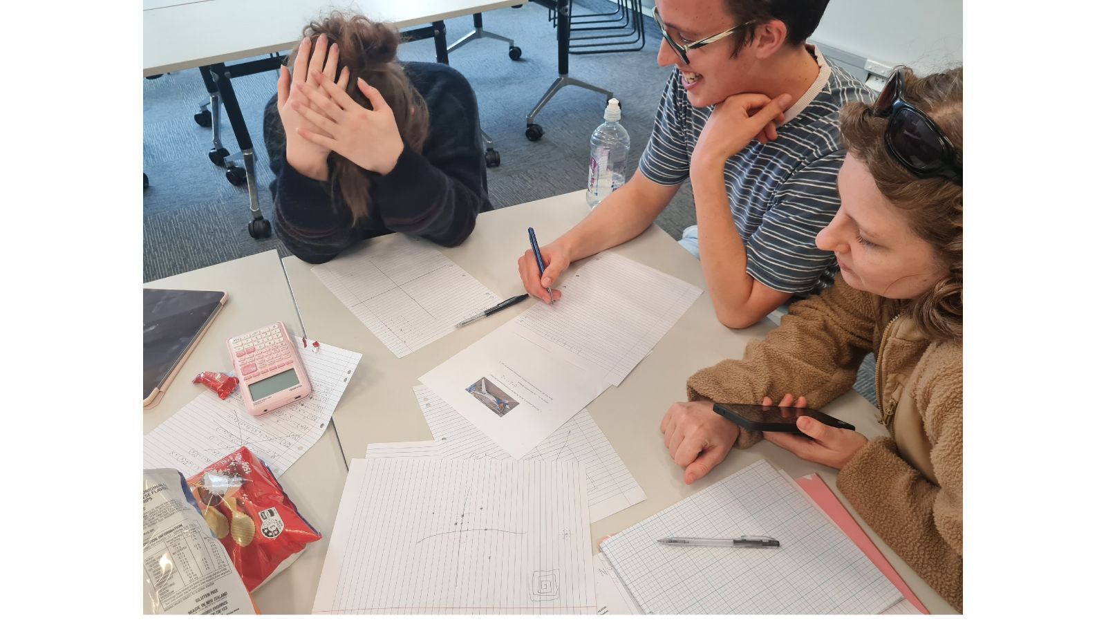 Students enjoying working on maths problems around a table.