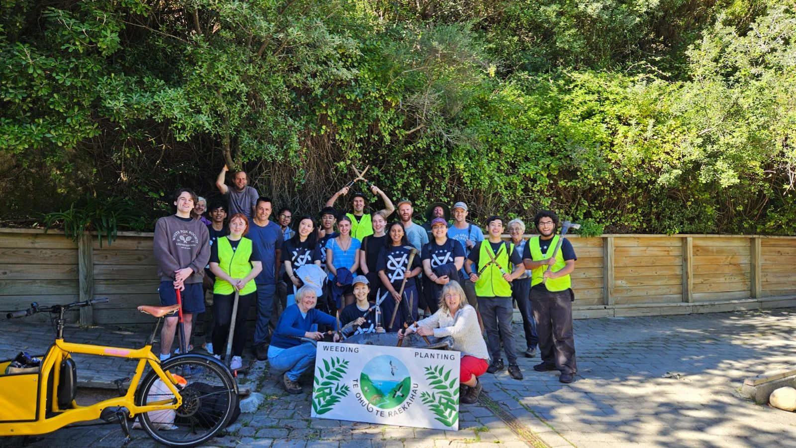 Group of students gathered together in gardening clothes with tools