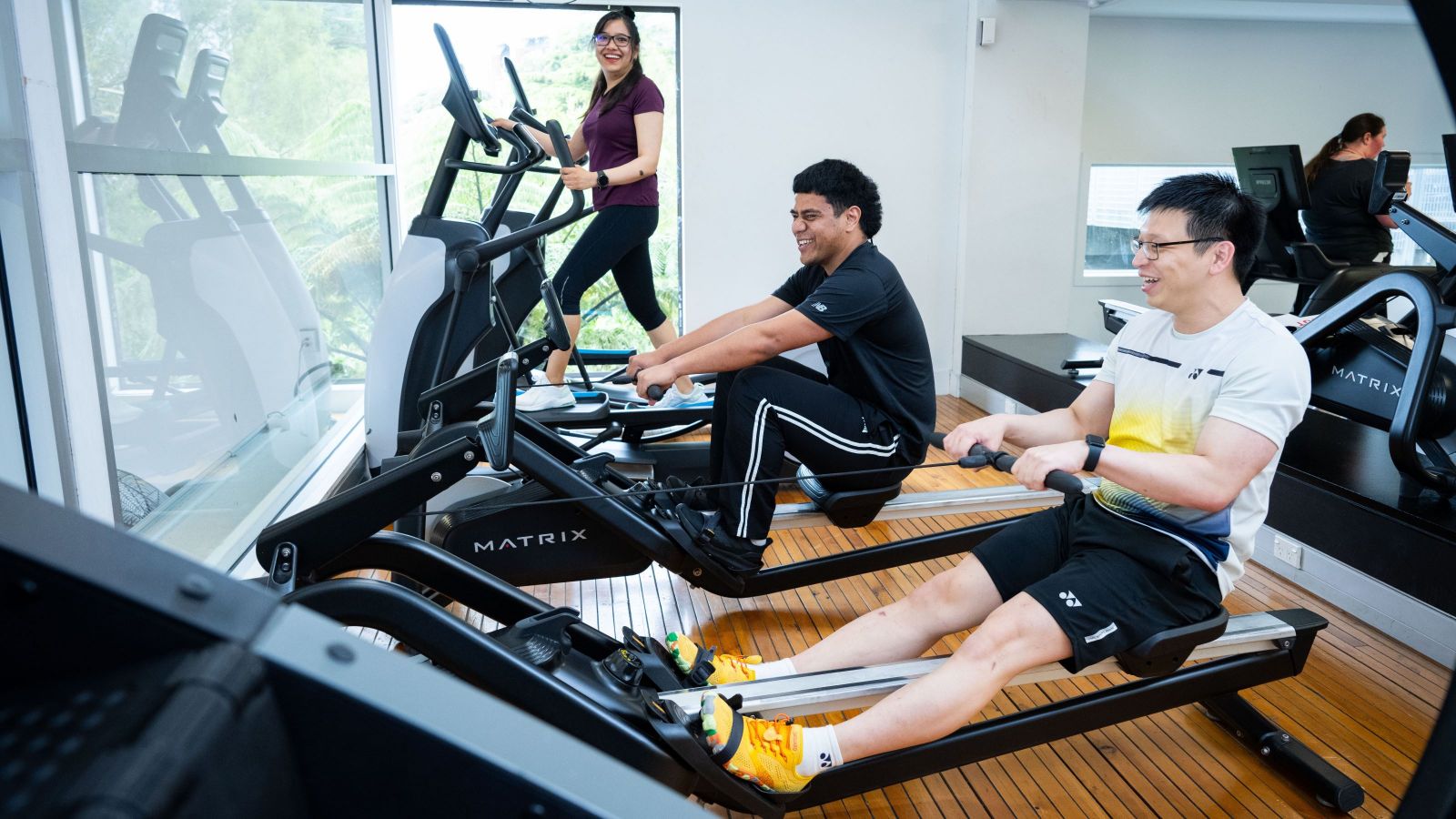 Three people using exercise machines in a gym