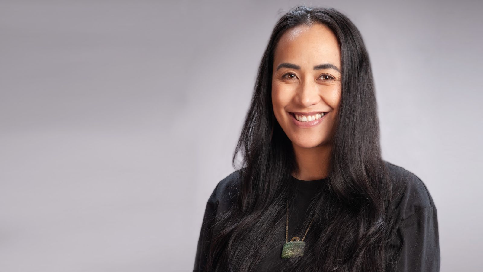 A woman with long black hair smiles at the camera