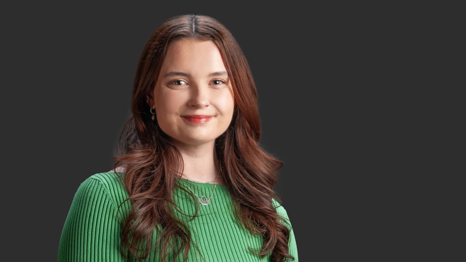 A young woman with long brown hair smiles at the camera