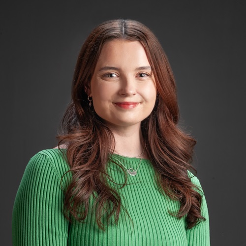 A young woman with long brown hair smiles at the camera