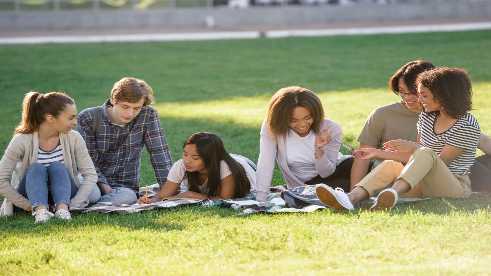 A group of students sitting outside on the grass and studying