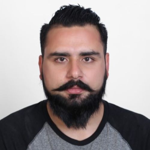 Man with dark hair and beard smiling at the camera