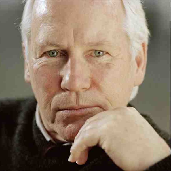 A man leans his face on his left hand and looks into the camera