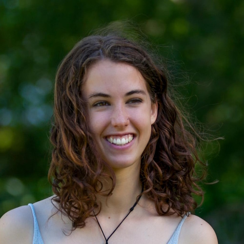 A profile photo of Molly Laurence, with blurry foliage in the background.
