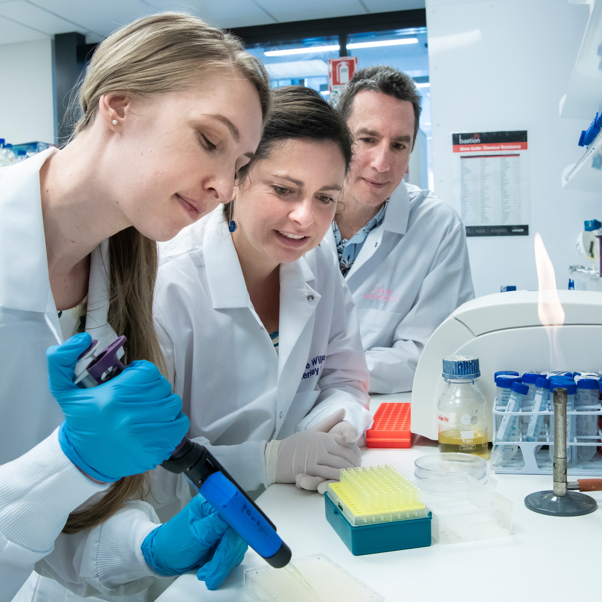 Students and researchers using a micropipette to prepare samples in a biotechnology laboratory.