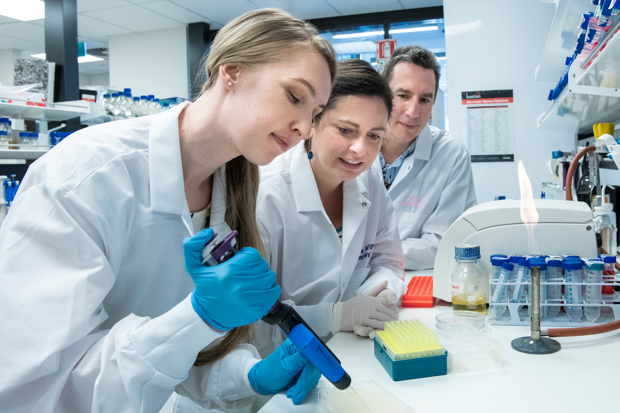 Students and researchers using a micropipette to prepare samples in a biotechnology laboratory.