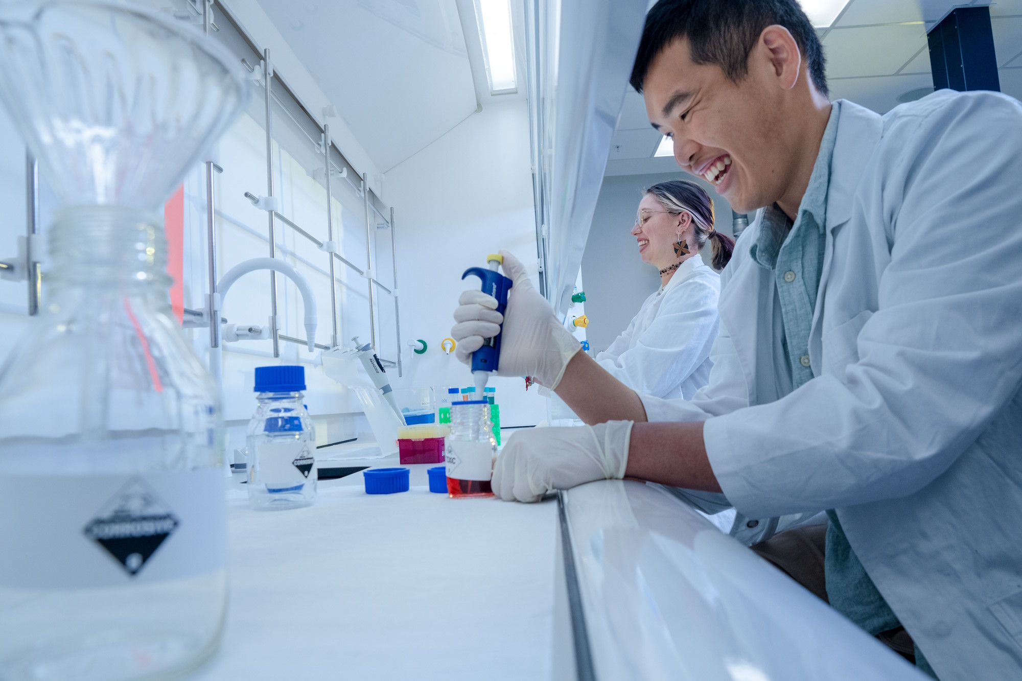 Students using pipettes to transfer liquid samples during a practical biology laboratory session.