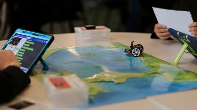 A table with students' hands around a table with a map acvitity