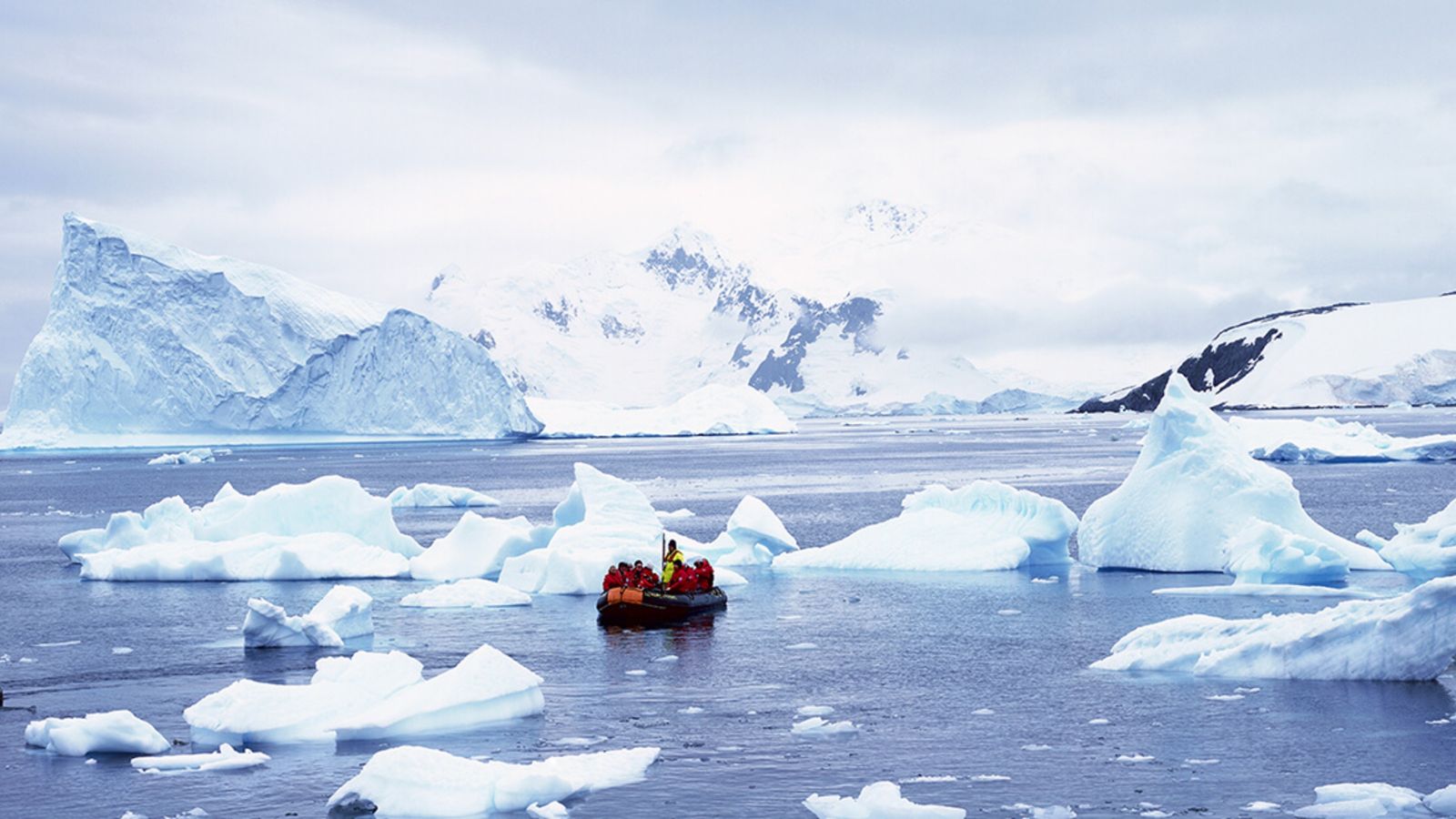 Small dinghy on sea surrounded by ice floes
