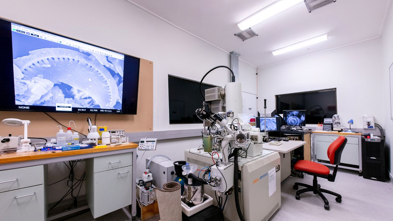 Room with large electron microscope, a large screen, and other equipment