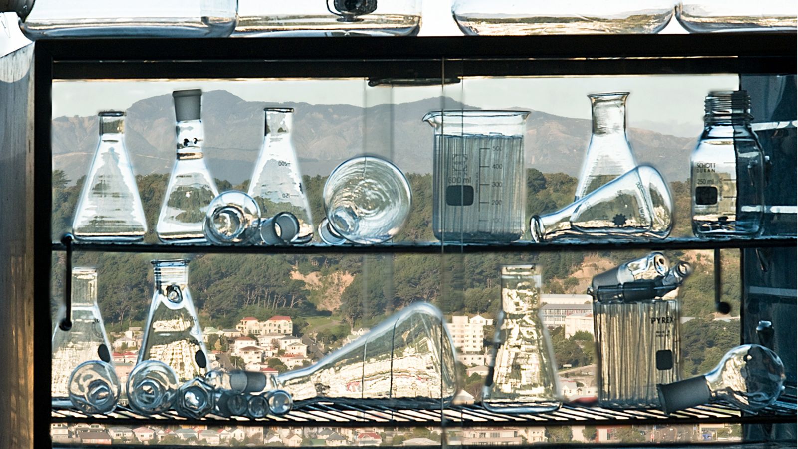 Several different shapes of glassware in a piewarmer with Wellington city visible in the background