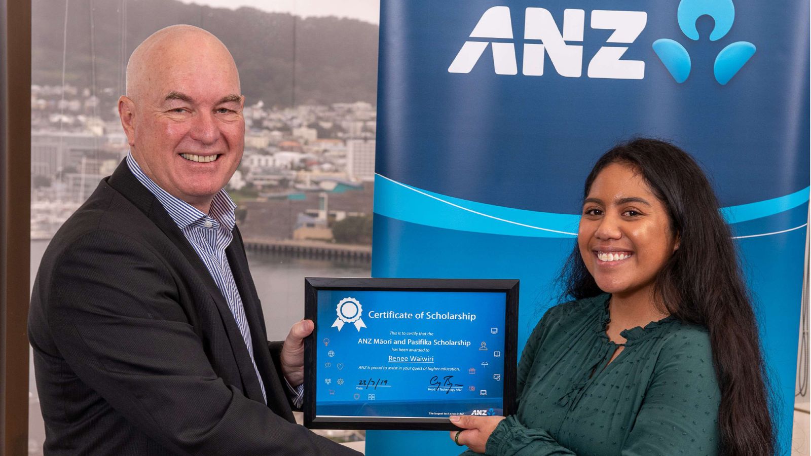 Renee accepts her scholarship certificate. Wellington harbour can be seen in the background.