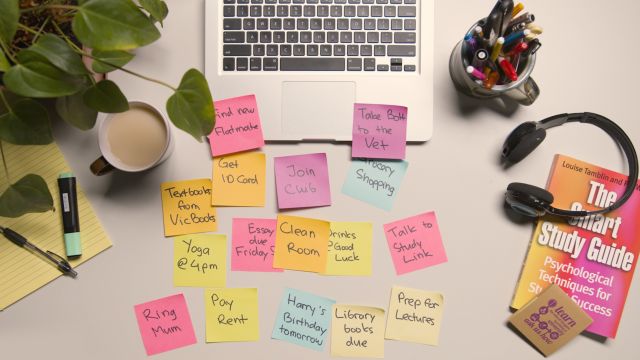 A birds eye view of a desk setup with a laptop and sticky notes.