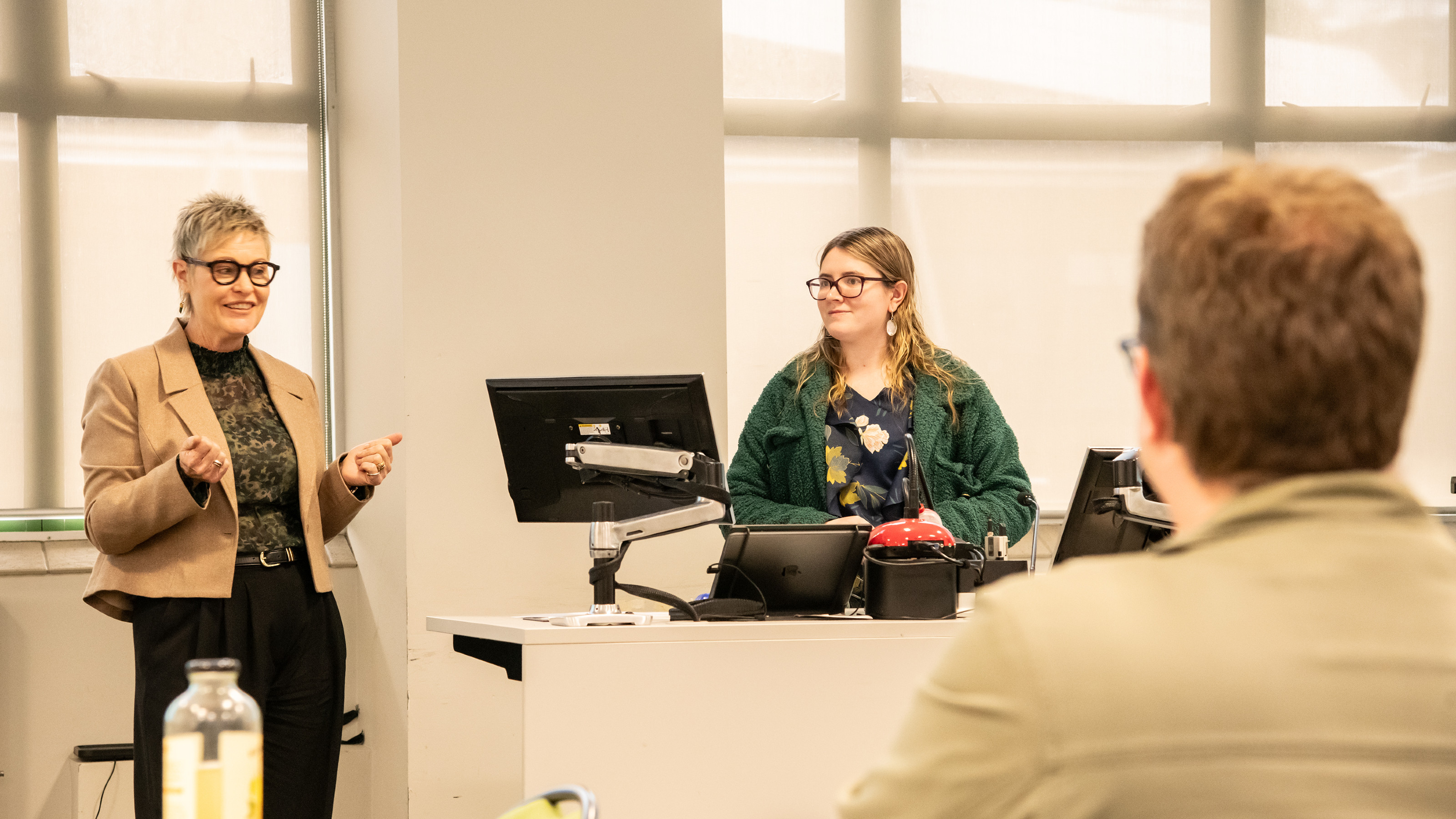 Imogen presenting a seminar in a beige-coloured room.