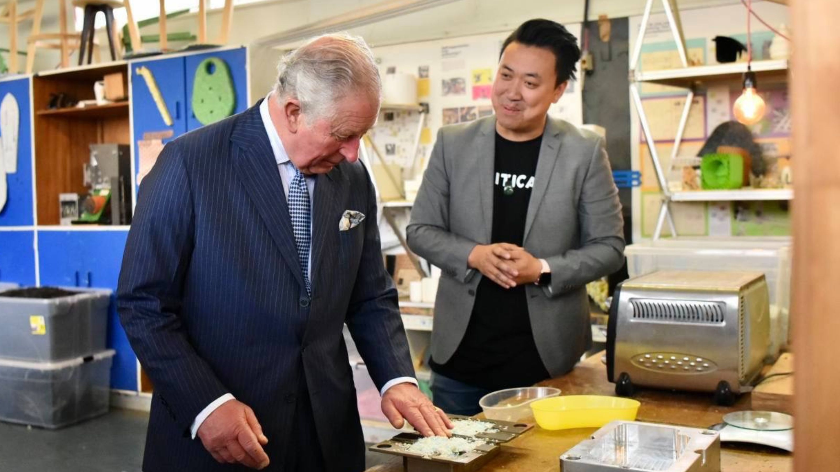 King Charles touches recycled plastic in a container on a table as he meets with Crticial. founder Rui Peng
