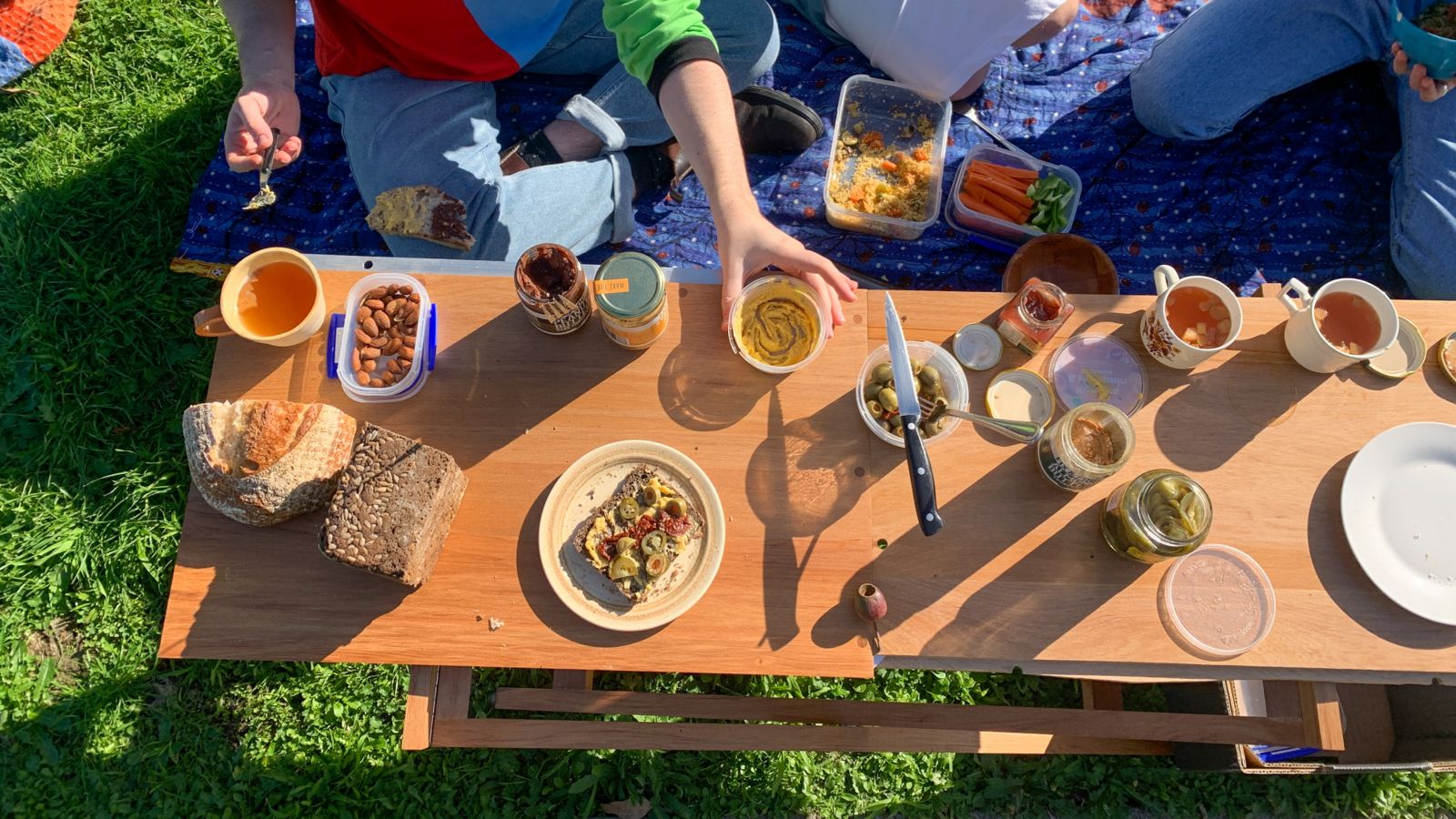 A to down view of a rimu table with food on at a picnic. 