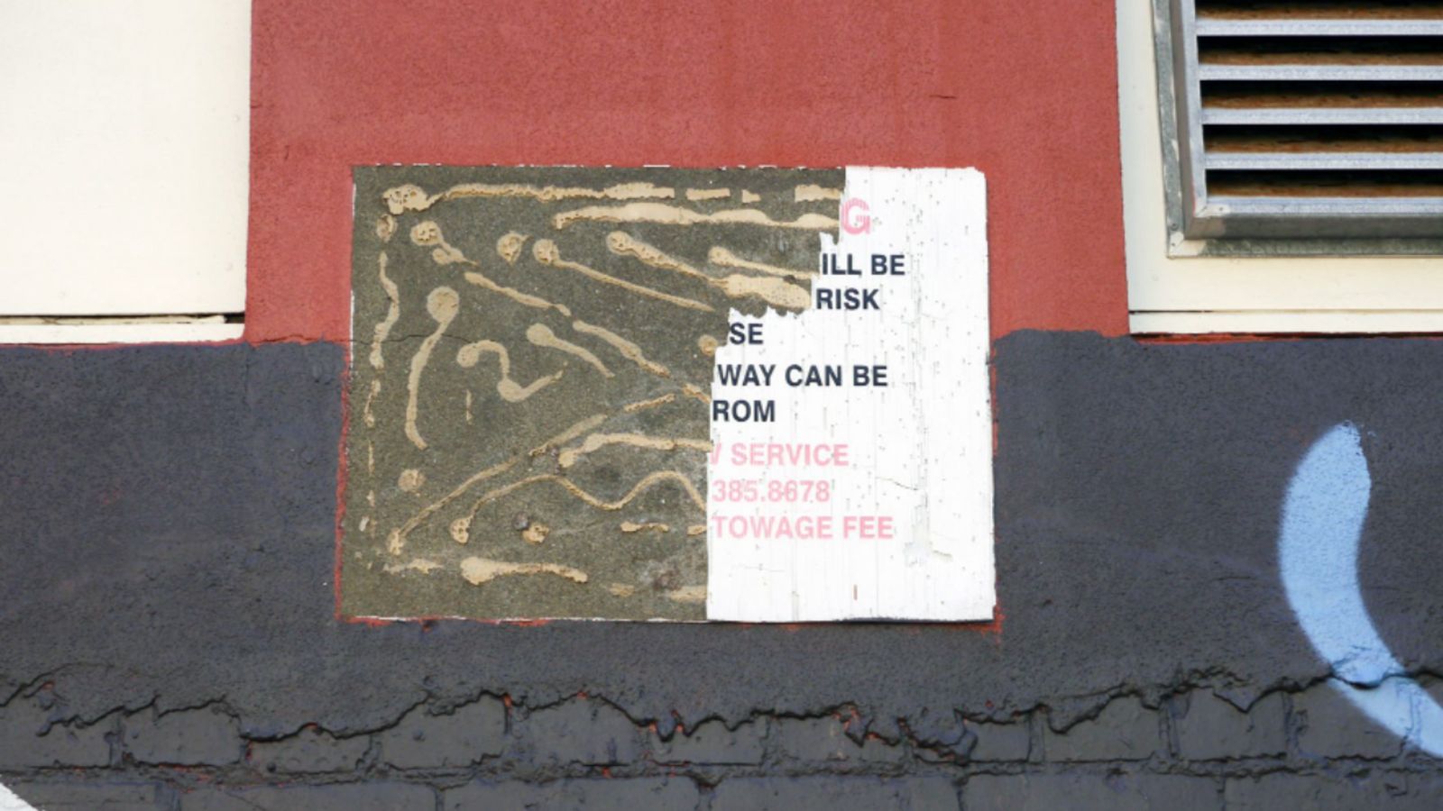 photograph of wall with remnants of glue after signage removed 